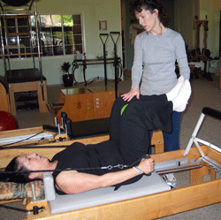 Photo: Pam instructing Judy in armwork on the pilates reformer.